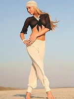 Long-haired blonde babe takes off her clothes on the beach